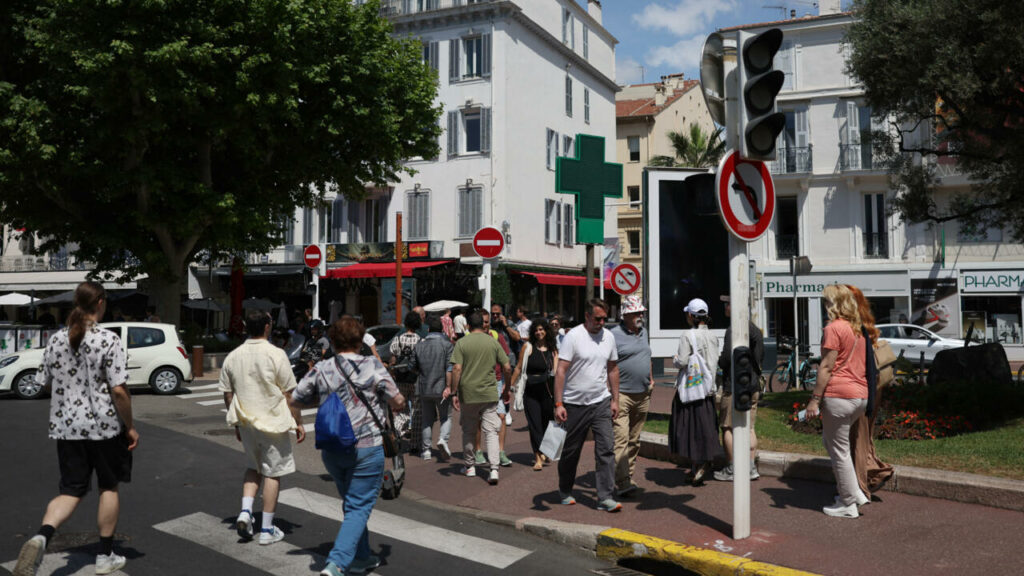 Des piétons traversent une rue à Cannes alors que les feux de circulation ne fonctionnent plus suite à une panne d'électricité dans le sud-ouest de la France, le 24 mai 2025. © Sameer Al-Doumy, AFP