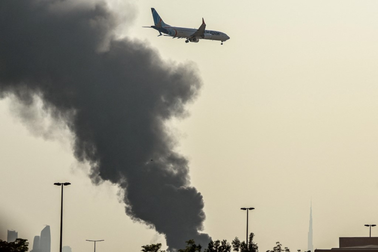 Un avion survole une panache de fumée provoqué par une frappe iranienne à Dubai, aux Émirats arabes unis, le 16 mars 2026. ©AFP