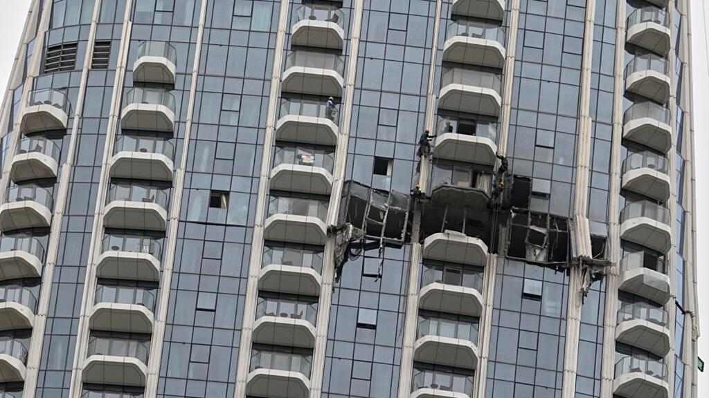 Des ouvriers inspectent les dégâts causés par une frappe de drone pendant la nuit à l'hôtel Address Creek Harbour à Dubaï, aux Émirats arabes unis, le 12 mars 2026.